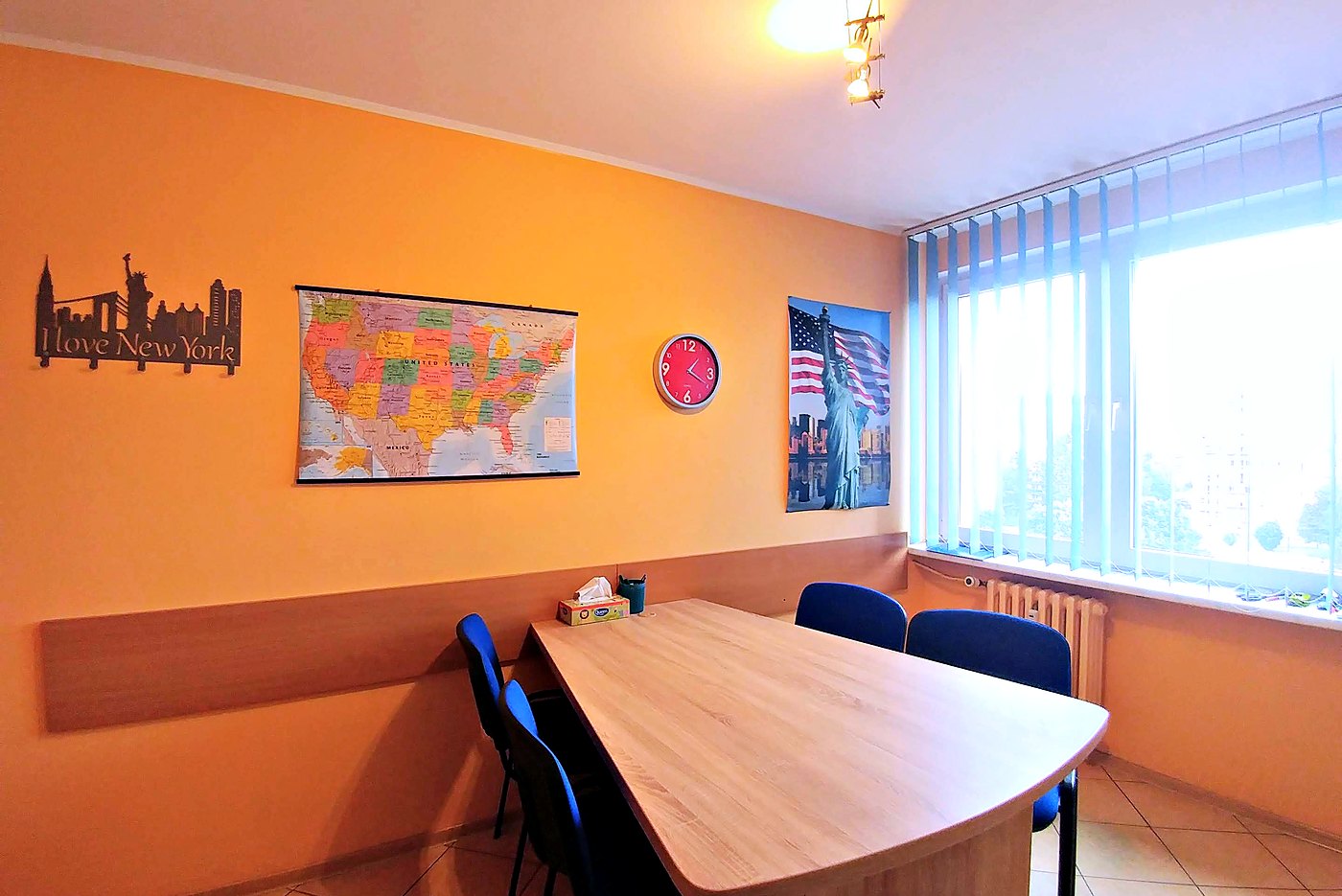 Pomarańczowa sala AcCentu: mapa Stanów Zjednoczonych, sylwetka Londynu na ścianie i długi stół przy oknie